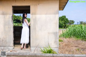 A woman sitting on the floor in a white dress.