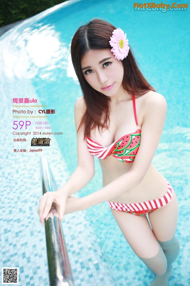 A woman in a bikini standing next to a swimming pool.