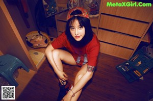 A naked woman holding a red skateboard on a black background.