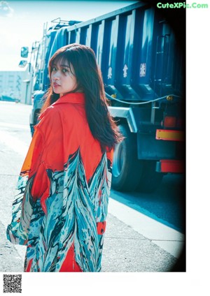A woman in a colorful kimono standing on a sidewalk.
