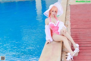 A woman in a pink bathing suit sitting by a pool.