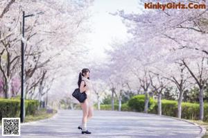 A woman in a pink lingerie posing in front of a tree.