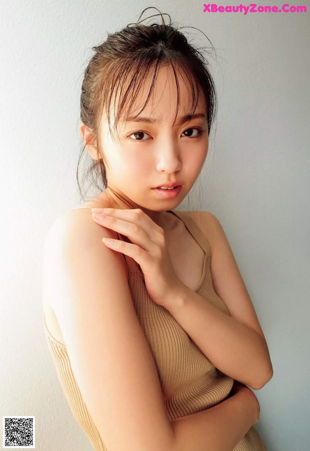 A woman in a tan tank top posing for a picture.