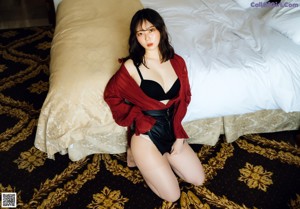 A woman sitting on the floor in a bedroom.