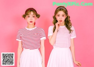two girls sitting at a table with strawberries on it