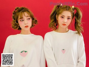 two girls sitting at a table with strawberries on it