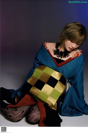 A woman in a blue kimono posing for a picture.