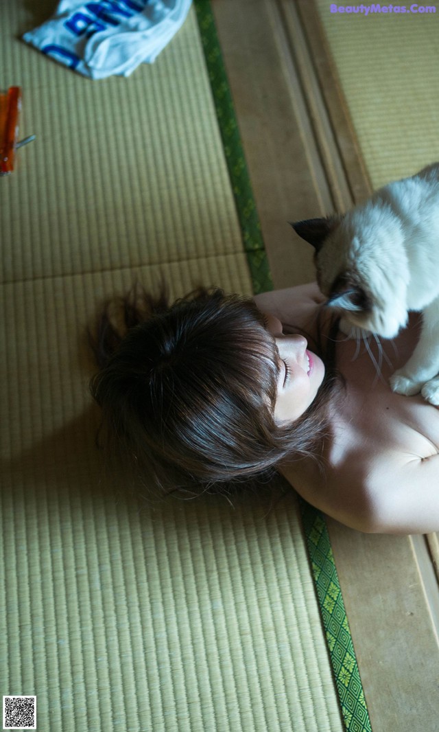 A woman laying on the floor with a cat on her shoulder.