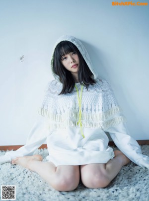 A woman in a white dress sitting on the ground.