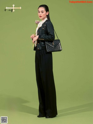A woman in a black suit and a black bag.