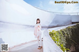 A woman standing in front of a white wall.