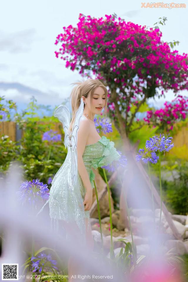 A woman in a green dress standing in a garden.