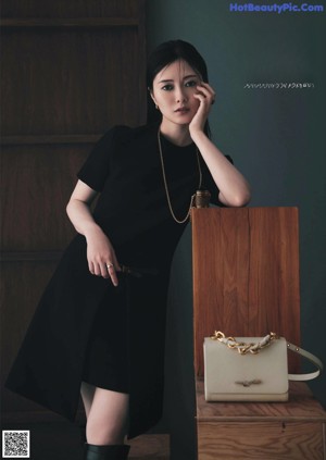 A woman standing on top of a pedestal holding a handbag.