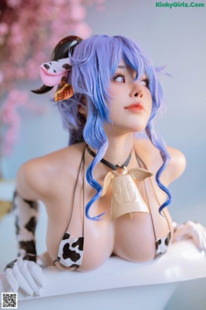 A woman in a cow print bikini sitting on a bed.