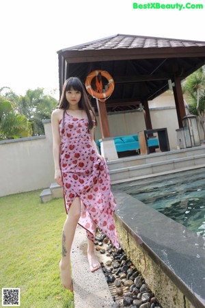 A woman in a pink dress sitting on some steps.