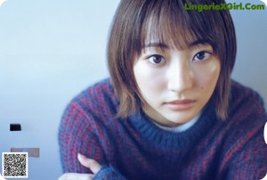 A woman sitting on a couch with her hand on her chin.