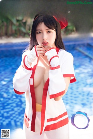 A woman in a red and white outfit posing by a pool.