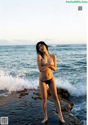 A woman in a pink bikini sitting on a surfboard.